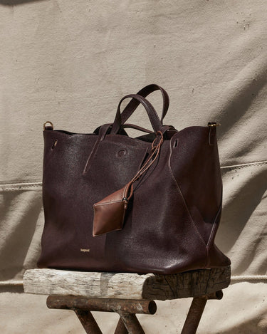 Deep brown pebbled leather tote bag with detachable pouch and 'Songmont' logo, displayed on rustic wood.