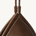 Prism Airpods Case in Sandal brown full-grain leather with white stitching and braided strap.