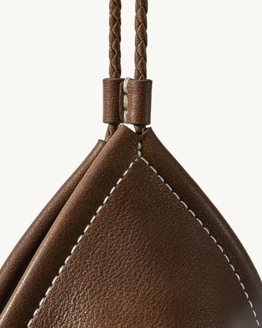 Prism Airpods Case in Sandal brown full-grain leather with white stitching and braided strap.
