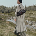Prism Seed Charm in Onyx, a curved shoulder bag with beaded charms worn by a woman in a trench coat.