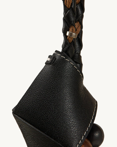 Black leather Prism Seed Charm with a braided strap and metallic accent.