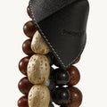 Prism Seed Charm in Onyx: black leather accent with embossed Songmont logo on a strand of mixed beads.
