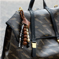 Sandal Prism Seed Charm with woven bodhi seeds and leather detailing attached to a patterned Songmont bag.