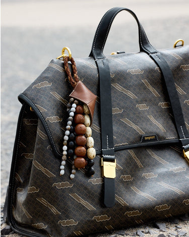 Sandal Prism Seed Charm with woven bodhi seeds and leather detailing attached to a patterned Songmont bag.