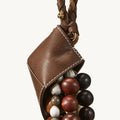 Brown leather pouch filled with mixed-color wooden and stone beads, attached to a braided strap.