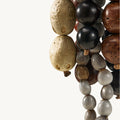 Prism Seed Charm accessory with diverse beads: textured light brown, smooth black, and marbled grey.