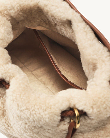 Inside view of amber shearling gather clutch bag, showing soft lining, leather pocket, and gold hardware detail.