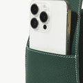 Green leather bag holds white iPhone Pro, showing camera and 'Songmont' logo.