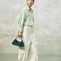 Green full-grain leather small drippy roof bag with microfiber lining, held by a woman.