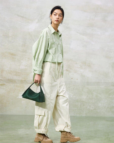 Green full-grain leather small drippy roof bag with microfiber lining, held by a woman.