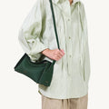 Small dark green full-grain leather drippy roof bag with textured finish and gold hardware.