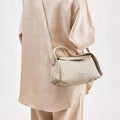 Ivory textured leather Small Drippy Roof Bag worn crossbody, with gold hardware.