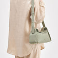 Light green full-grain leather Small Drippy Roof Bag with textured finish, flap closure, and adjustable strap.