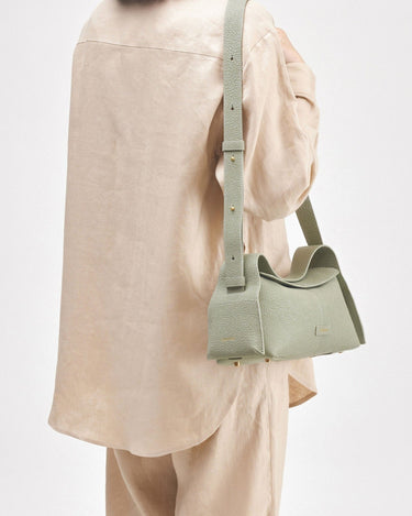 Light green full-grain leather Small Drippy Roof Bag with textured finish, flap closure, and adjustable strap.