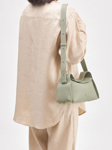 Light green full-grain leather Small Drippy Roof Bag with textured finish, flap closure, and adjustable strap.