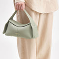 Small light green pebbled full-grain leather handbag with gold branding. Adjustable strap.
