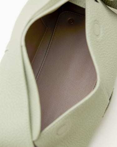 Light green full-grain leather small drippy roof bag interior with taupe lining and gold snap closure