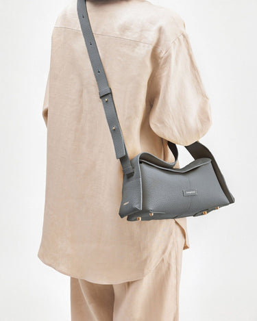 Grey full-grain leather crossbody bag with gold hardware, "Songmont" embossed on front flap.