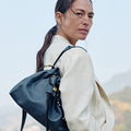 Navy Small Gather Bag Set carried by a woman, showcasing its textured leather and unique charm details.