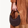 Small Luna Bag in burgundy full-grain leather with gold hardware and clasp detail.