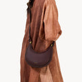 Burgundy textured leather Small Luna Bag worn crossbody with gold hardware.