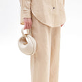 Small Luna Bag in ivory pebbled leather, held by hand with a looped handle and gold hardware.