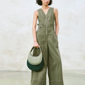 Small Luna Bag in Jade featuring dual-tone leather and gold hardware, held by a model in a green jumpsuit.
