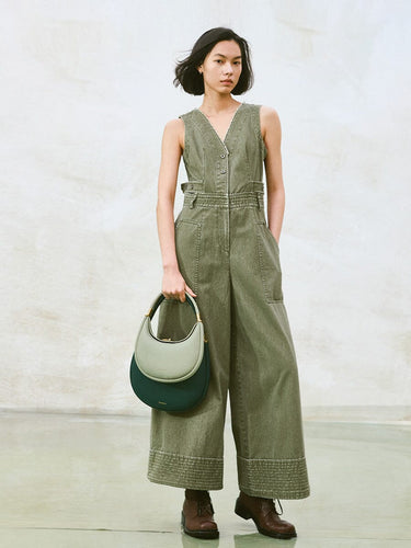 Small Luna Bag in Jade featuring dual-tone leather and gold hardware, held by a model in a green jumpsuit.