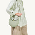Small Luna Bag in Jade green pebbled leather with a curved silhouette and gold hardware.