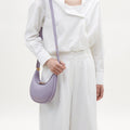 Lavender pebbled leather Small Luna Bag worn by a woman in a white shirt and wide-leg pants.
