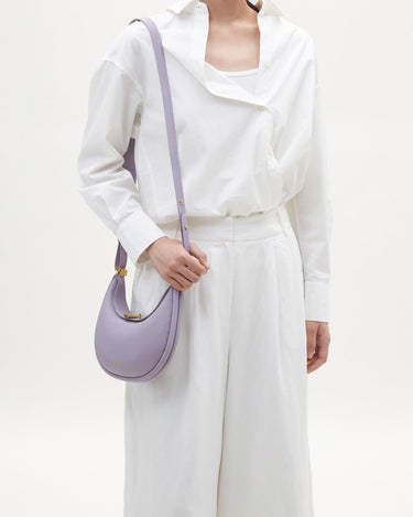 Lavender pebbled leather Small Luna Bag worn by a woman in a white shirt and wide-leg pants.