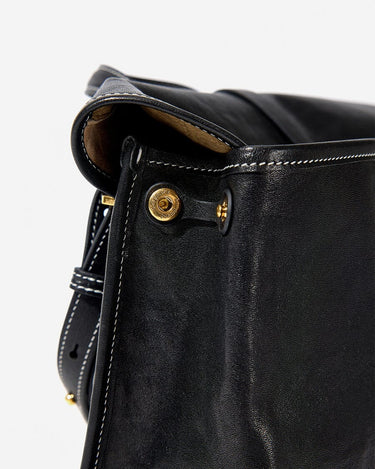 Black Small Shan Satchel Bag with white stitching and gold hardware. Vegetable-tanned leather detail.