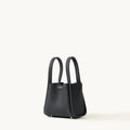 Small black full-grain leather Song bag with top handles and magnetic closure.