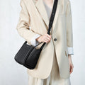 Black full-grain leather Small Song Bag with pebble texture and magnetic closure worn crossbody by a model.