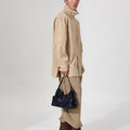Small Yore Hobo Bag in Onyx carried by a model in beige attire.