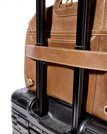 Sandal leather Large Shan Briefcase secured to suitcase handle. Features white stitching & 'songmont' branding.