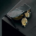 Yore Glasses Case: Black leather, white stitching, gold-rimmed sunglasses, reflective gold lenses, snap closure.
