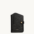 Black Songmont Yore Passport Case in vegetable-tanned leather with gold snap closure and white stitching.