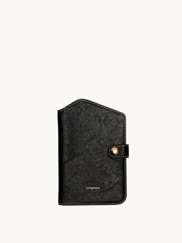 Black Songmont Yore Passport Case in vegetable-tanned leather with gold snap closure and white stitching.