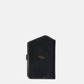 The Yore Passport Case in Onyx black vegetable-tanned leather with a tiger tooth detail and snap closure.