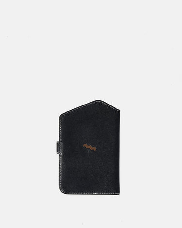 The Yore Passport Case in Onyx black vegetable-tanned leather with a tiger tooth detail and snap closure.