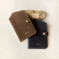 Yore Passport Case in brown and onyx, vegetable-tanned leather with gold snap closure and white stitching.