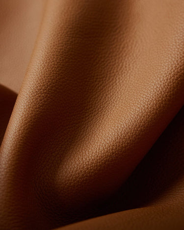 Close-up of caramel-colored full-grain leather with visible grain texture, showcasing the material of the Wish Seeds Charm.