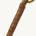 Caramel leather-wrapped charm with a gold ring and braided cord.
