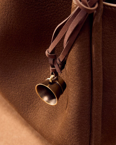 Sandal colored Worry-Free Cup Charm with aged metal finish and leather tie