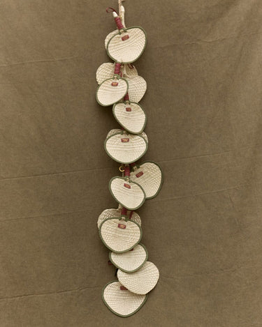 Woven fan charm garland made of heart-shaped palm frond fans with green trim and red tags.