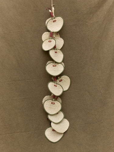 Woven fan charm garland made of heart-shaped palm frond fans with green trim and red tags.