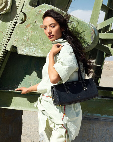Woman with black Yore Baguette Bag in onyx, featuring vegetable-tanned leather and stainless steel hardware.