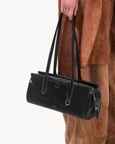 Black Yore Baguette Bag by Songmont, crafted from vegetable-tanned leather with white stitching and gold hardware.