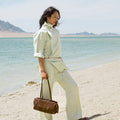 Yore Baguette Bag in Sandal color, made of vegetable-tanned leather, on a beach.